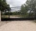 Black arched driveway gate between stone columns in Edinburg
