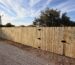 Wood privacy fence and matching gates with black hinges along a La Feria property.