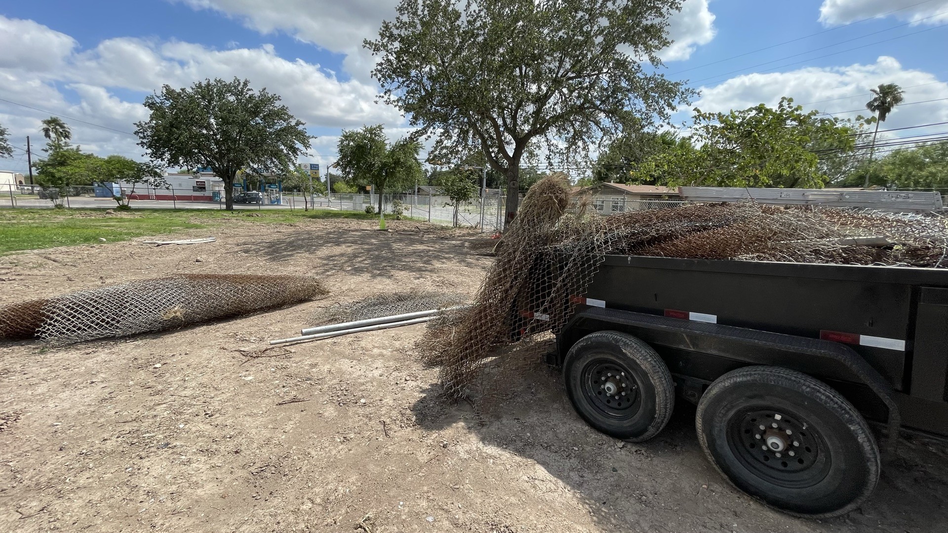 Rolls of removed chain link fabric beside and on a trailer at the water-tower site.